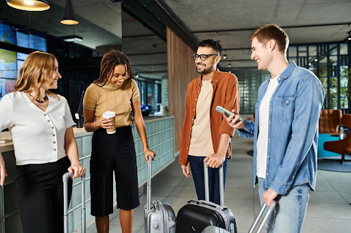 A group of four corporate officers chatting in a hotel lobby with their wheeled carry-on luggage; assembling for a corporate retreat.