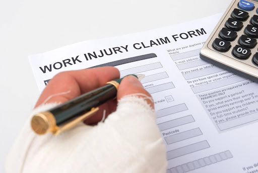 A hand with a cast filling out a workers’ compensation claim form. Understanding the role of the experience modification rate helps in understanding the safety of a company's workplace.
