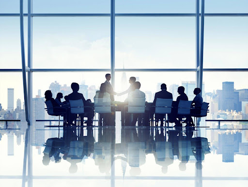 Employees working in a boardroom, indicating the importance of protecting your business from class action lawsuits.