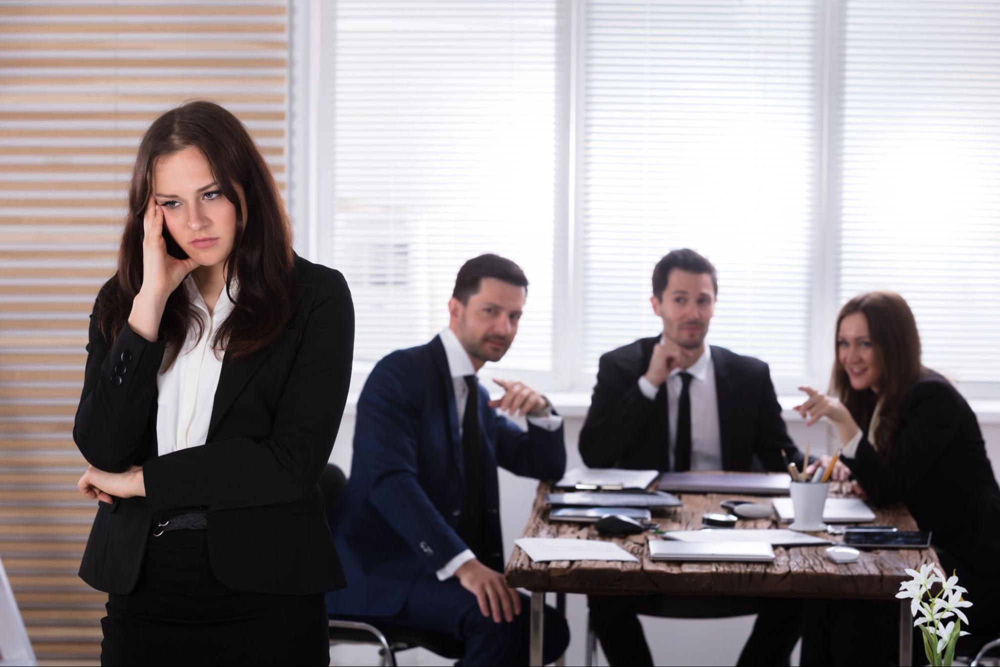  Image depicting workplace harassment during hiring or promotion, where an employee appears isolated while colleagues engage in inappropriate behavior.
