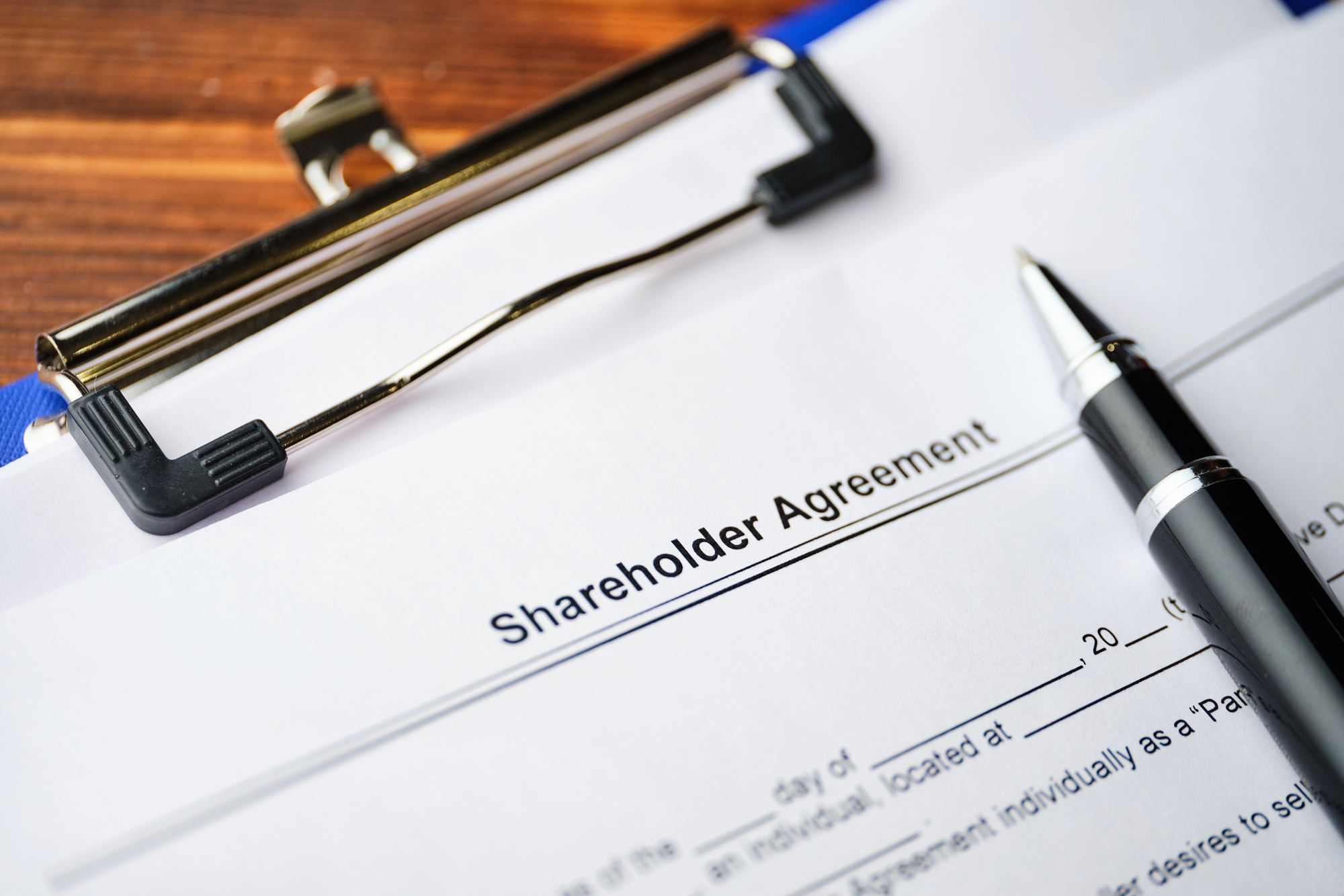 Image of a shareholder agreement on a clipboard with a pen, representing protecting investors, legal risks, business partnerships, and corporate decision-making.