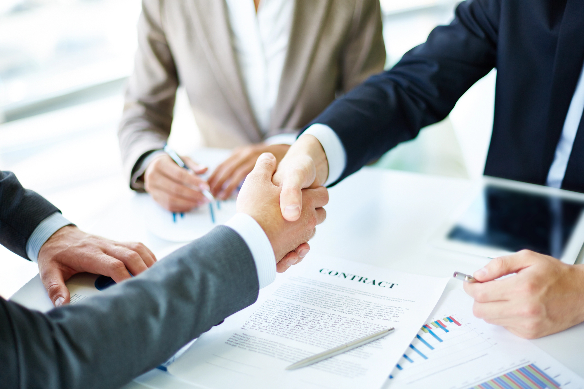 Business professionals shaking hands over a contract, representing commercial agreements, risk management, and collaboration in business litigation matters.