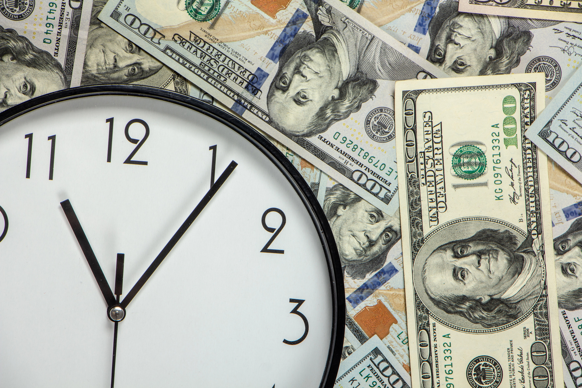 A clock surrounded by dollar bills; managing employee work hours is essential for employers. 